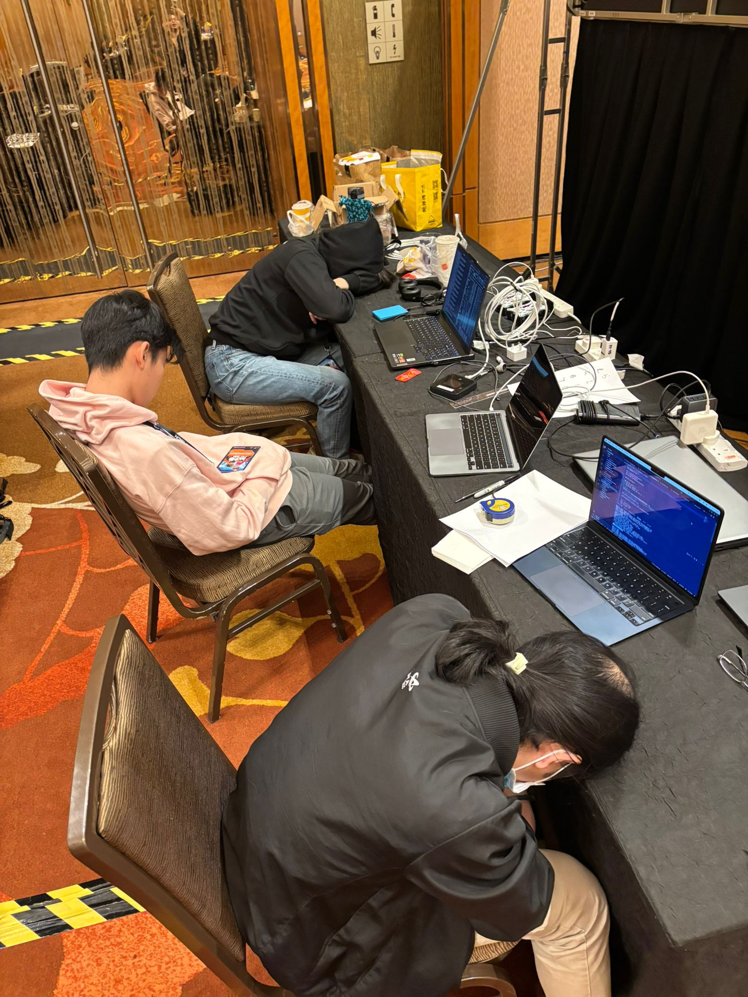 The tech team asleep in the organizers' corner, sometime between 6am and 7am on competition day. From top to bottom: me, Tianshi, Ryan.